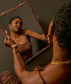 a woman is looking at her reflection in the mirror while wearing gold jewelry and bracelets