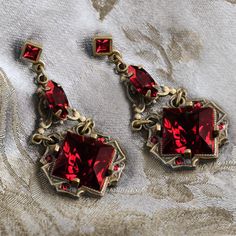 "Richly colored authentic circa 1930s glass squares from Bohemian Czechoslovakia are featured in these Art Deco link earrings. Set diagonally in pronged open back deco settings, the squares are joined with detailed vintage links mounted with marquis stones of the same color. A small faceted square stone is set in the post top. A slinky, artistic vintage geometric design that was a favorite of the Cafe Society. Choice of emerald green, garnet red or amethyst purple crystal. Burnished bronze finis Vintage Garnet Earrings, Czech Jewelry, Lavender Earrings, Pastel Earrings, Aqua Earrings, Garnet Red, Green Garnet, Square Stone, Link Earrings