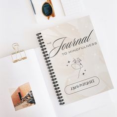 a spiral notebook with the words journal to mindfulness written on it next to other items