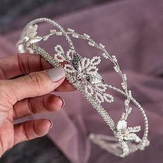 a woman is holding a tiara in her left hand and wearing it on the other hand