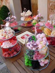 a table topped with lots of different types of candies and desserts on top of glass trays