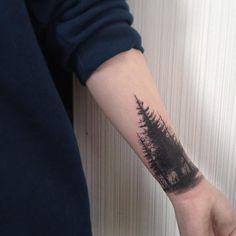 a person's arm with a small tree tattoo on the left side of their arm