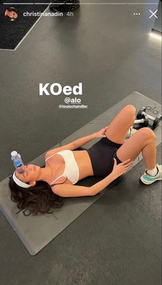 a woman laying on top of a yoga mat with a water bottle in her hand