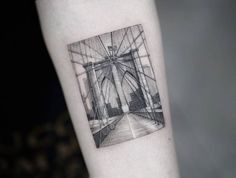 a black and white photo on the arm of a person with a bridge in the background