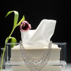 a stack of white napkins sitting on top of a table next to a flower