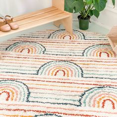 an area rug with rainbows on it next to a wooden bench and potted plant