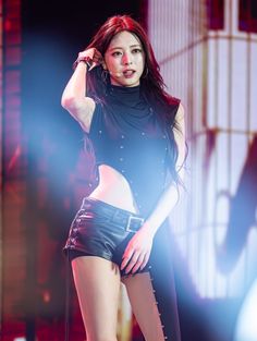 a woman in short shorts and black top on stage with her hands behind her head