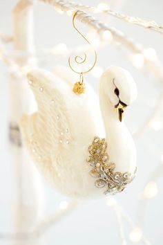 a white swan ornament hanging from a christmas tree with lights in the background