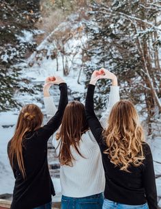 three women standing in the snow with their hands up