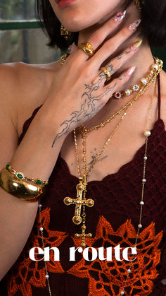 a woman with her hands on her chest wearing gold bracelets and cross necklaces