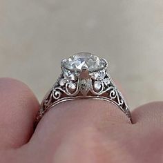 a close up of a person's hand holding a ring with a diamond in it