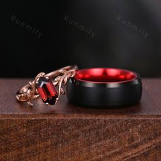 two wedding rings on top of a wooden table with red glass in the middle and gold chains around them