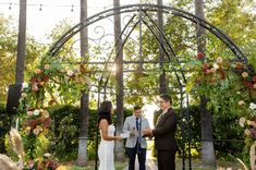 a bride and groom are standing under an arch at their wedding ceremony in the park