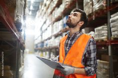 a man in an orange safety vest is looking up at the sky while holding a clipboard