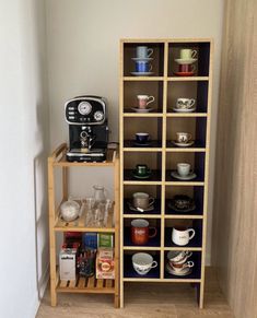 there is a shelf with cups on it next to a coffee maker