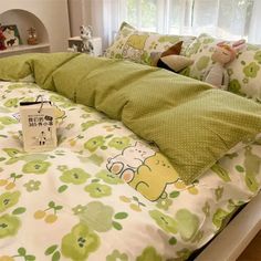 a bed with green and white sheets, stuffed animals on the headboard next to it