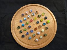 a wooden plate with many different colored glass knobs on it's side, sitting on a black surface