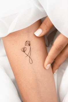 a woman's leg with a small flower tattoo on the left side of her thigh