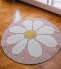 a pink and white rug with a flower on the floor in front of a window