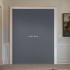 a large blue door is in the middle of a room with two pictures on the wall