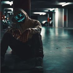 a man sitting on the ground wearing a neon mask