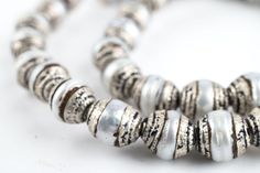 a close up of a bead necklace on a white surface with black and white stripes