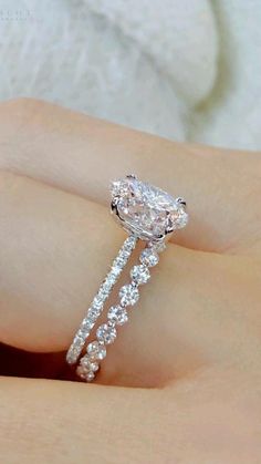 a woman's hand holding an engagement ring with a large diamond on the side