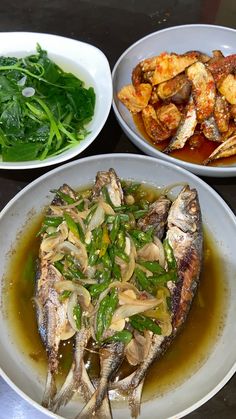 three plates of food on a table with vegetables and sauces in them, including fish