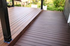 a wooden deck with black posts and blue tape on it's edge, under a pergolated roof