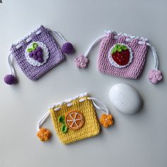 three crocheted purses sitting on top of a table next to a computer mouse