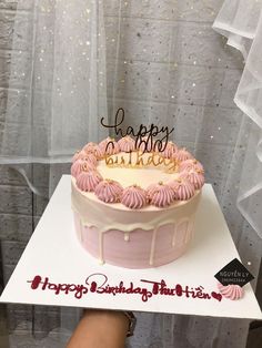 a birthday cake with pink frosting and gold sprinkles sitting on top of a table