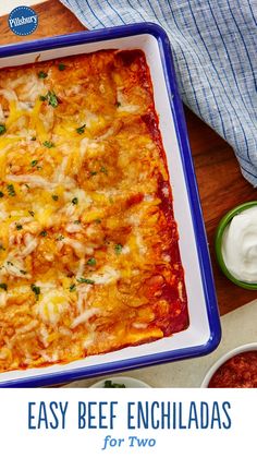 an easy beef enchiladas recipe in a casserole dish with sour cream on the side