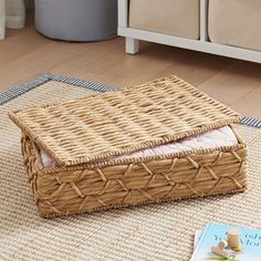 a wicker box sitting on the floor next to a book