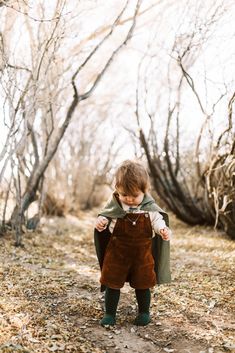 a little boy that is standing up in the dirt with his hands on his hips