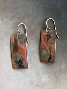 "Raku art-form hand enameled solid copper earrings. Length: 1 1/2\" I use the highest quality USA solid copper. Each copper piece is hand torched, and then enameled by hand with cold enameling in small batches. Through a special process, I mirror each pair of earrings to be complementary. I've been hand-torching metals for over two decades, perfecting the art of natural aging. Adding cold enameling has been a sheer delight. For these earrings, I used a combination of different cold enamels to achieve a raku art-form. The ear wires are copper vermeil over solid brass. USA findings. Each pair has its own qualities and unique beauty. I create these in small batches, so they will be similar to what is in the photographs. I've included a photo of the variances you'll find between each pair of e Artsy Bronze Earrings For Gift, Bronze Artsy Earrings For Gifts, Artisan Rust-colored Earrings As Gift, Artistic Hand Painted Copper Earrings, Artistic Copper Earrings With Patina, Hand Painted Copper Artsy Earrings, Hand Painted Artsy Copper Earrings, Artsy Hand Painted Copper Earrings, Artistic Bronze Earrings With Patina