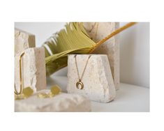 the gold necklace is on display next to some rocks and palm fronds in front of it