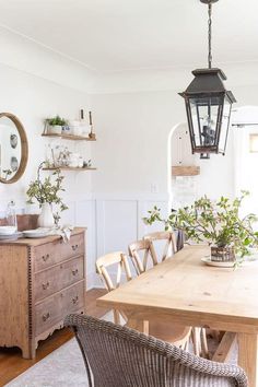 a dining room table with chairs and a lamp hanging from it's side wall