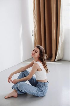 a woman sitting on the floor in front of a window