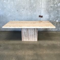 a wooden table sitting in front of a concrete wall