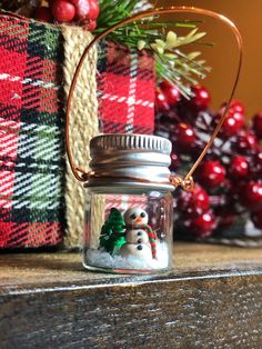 a glass jar filled with snowmen sitting on top of a wooden table next to christmas decorations