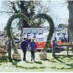 two people are walking in front of an old double - decker bus at a wedding