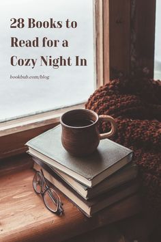 a stack of books sitting on top of a window sill next to a cup