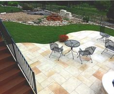 an outdoor patio with tables and chairs next to a fire pit in the back yard