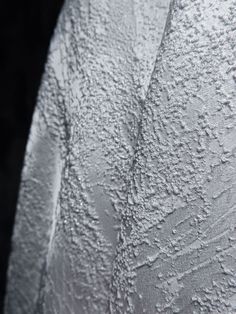 the back side of a white shirt with water droplets on it's surface and black background