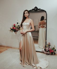 a woman standing in front of a mirror wearing a dress with slits on the side