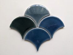 three blue and green tiles on a white wall in the shape of an abstract design