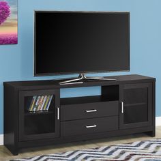 a flat screen tv sitting on top of a black entertainment center next to a blue wall