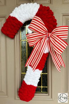 a red and white wreath hanging on the front door with a santa claus stocking