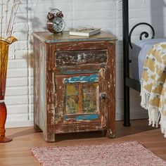 a small wooden cabinet sitting on top of a hard wood floor next to a bed