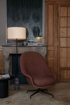 an egg chair sits in front of a fireplace with a lamp on the end table